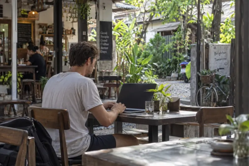 Un jeune homme travaille sur son ordinateur dans un café